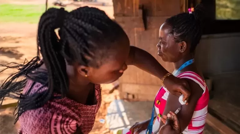 A person receives a vaccine from a community healthcare worker in sub-Saharan Africa.